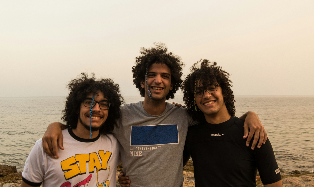 Three men smiling at the beach